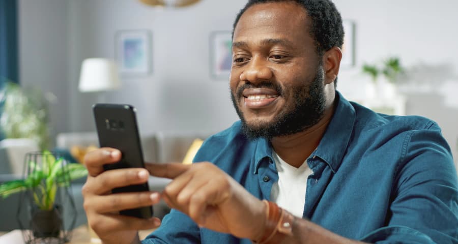 Man in his home interacting with an app on his smartphone